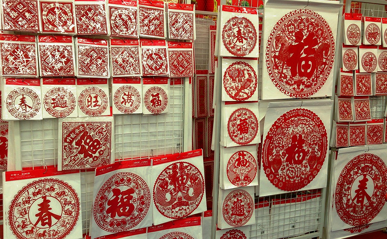 A shop display rack of assorted red paper cuttings for Chinese New Year with fortune characters, zodiac animals, and floral designs