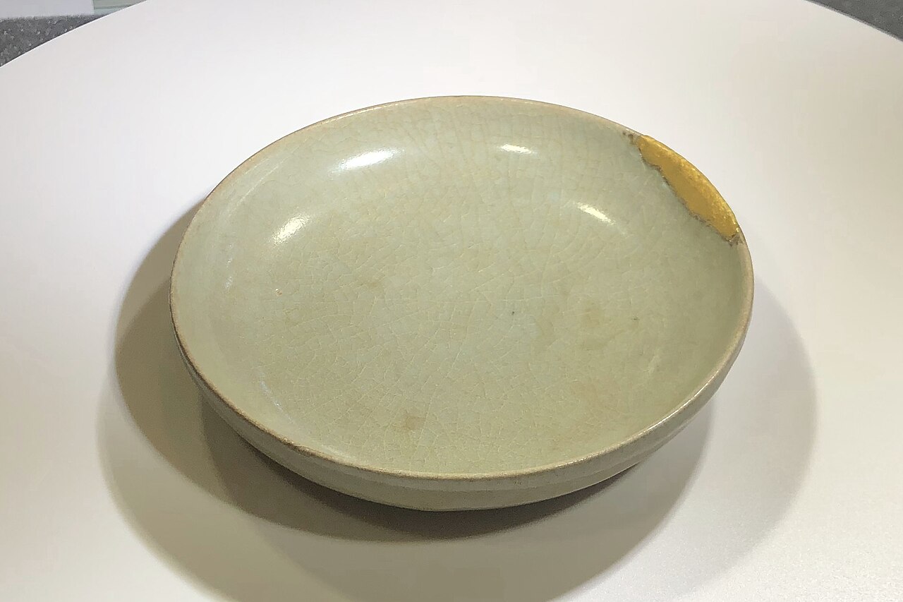 Song dynasty celadon dish with pale crackle glaze and a gold kintsugi repair on the rim