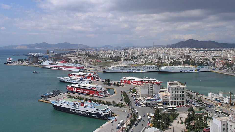 Aerial view of the Port of Piraeus showing passenger ferries from Minoan Lines, ANEK Lines, and Hellenic Seaways with the city in the background