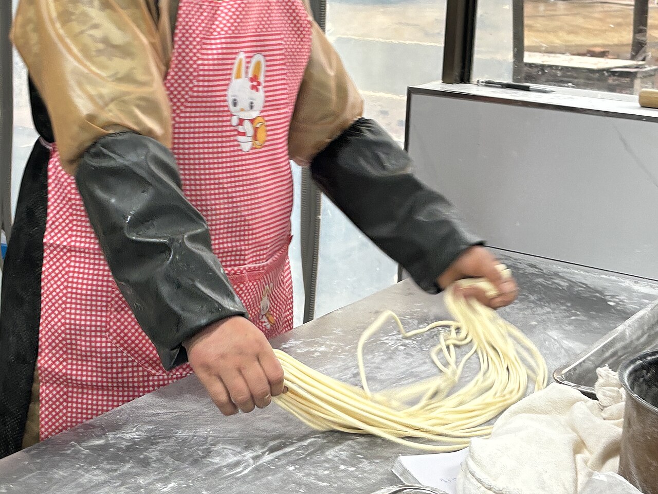 Chinese chef hand-pulling lamian noodles with stretched dough in mid-air