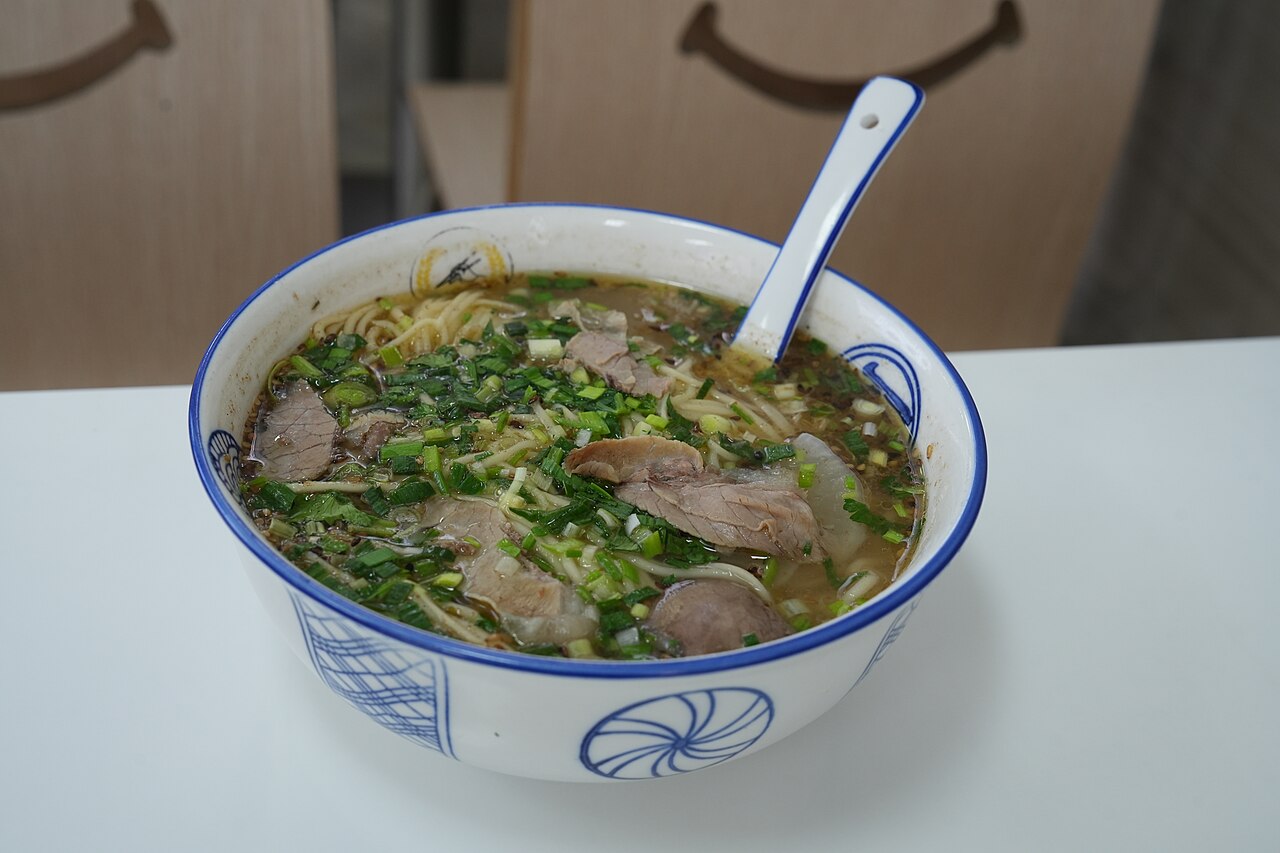 A bowl of Lanzhou beef noodle soup with garnishes