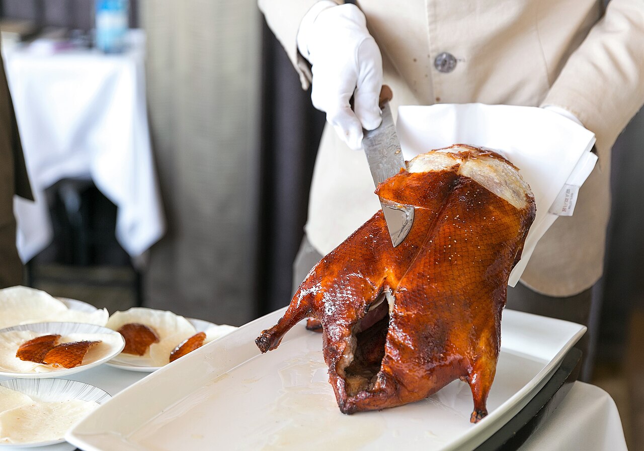 Peking duck being carved tableside into thin slices