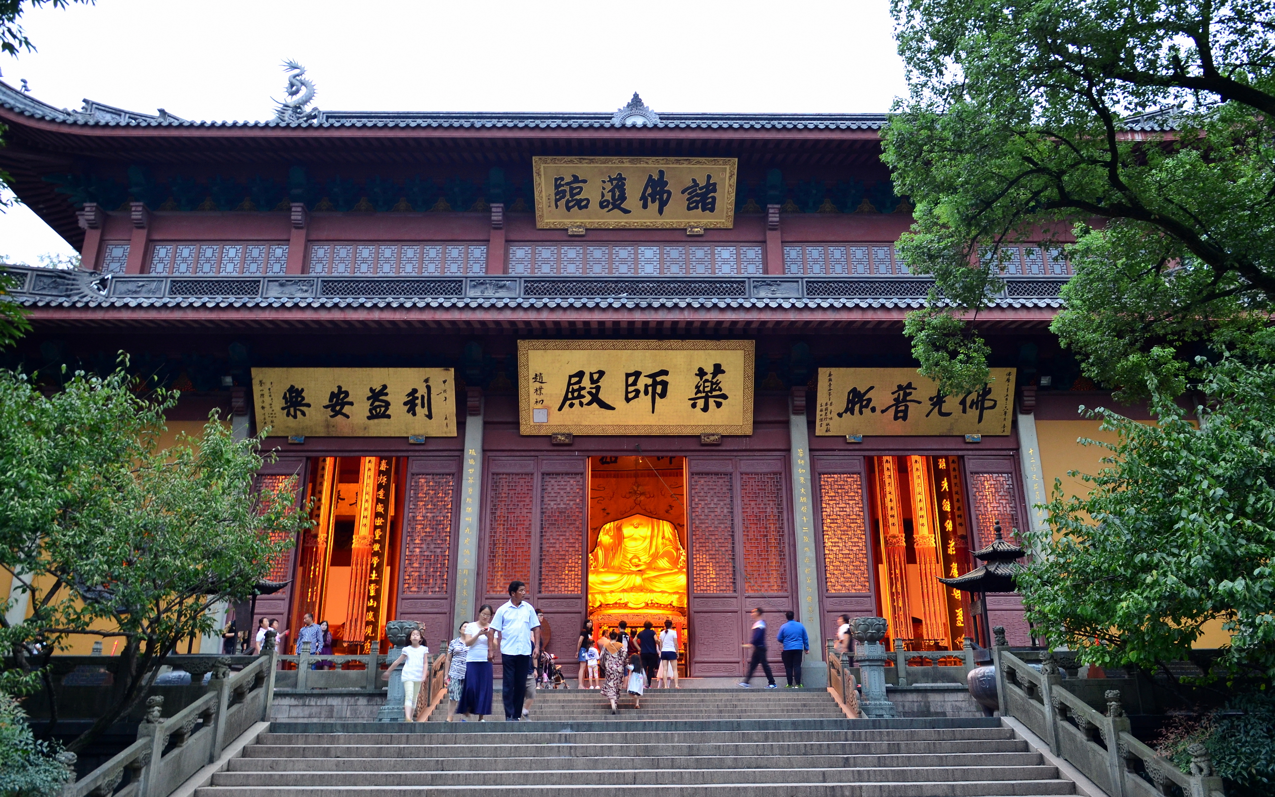 Exterior of the Medicine Buddha Hall (Yaoshi Dian) at a Chinese Buddhist temple, with visitors on the steps and a golden Buddha visible inside