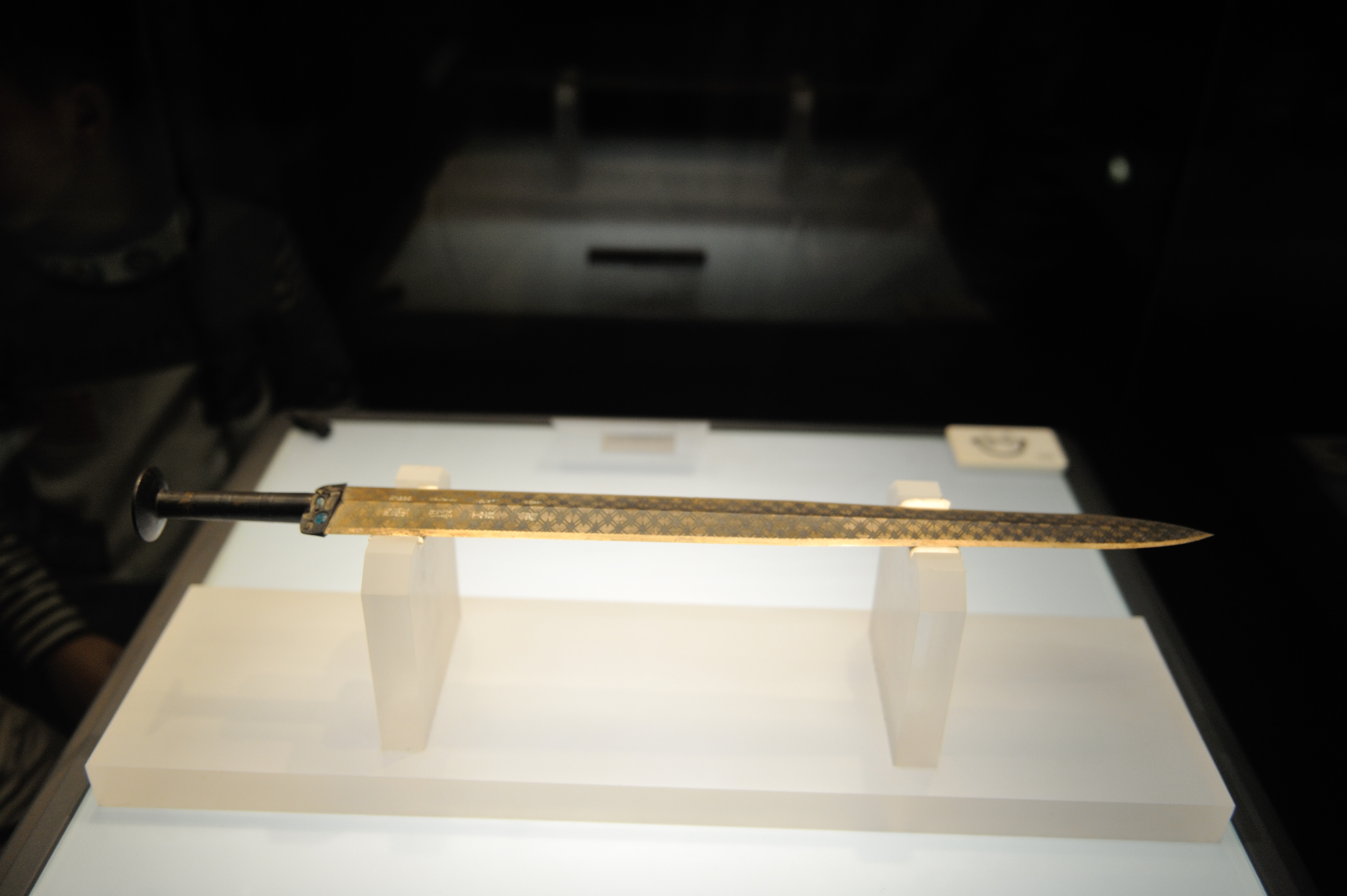 Ancient Chinese bronze sword with diamond pattern on display in a museum case