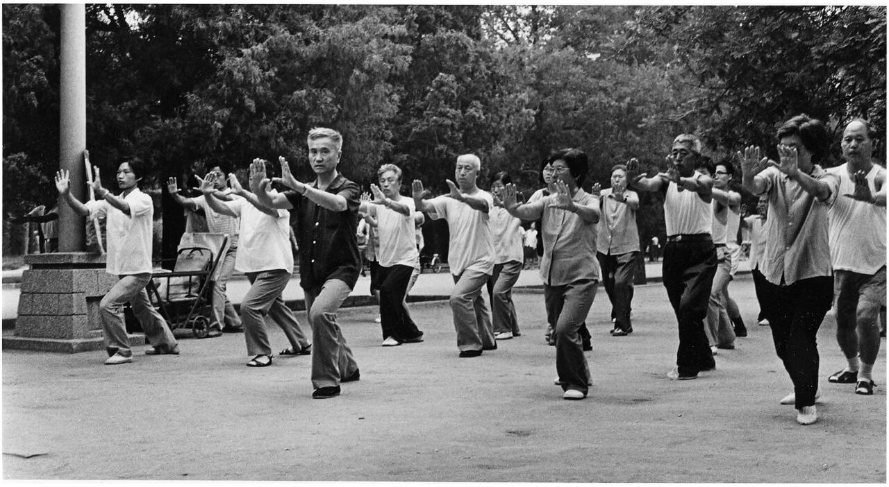Black and white photograph of elderly Chinese people practicing tai chi together in a Beijing park