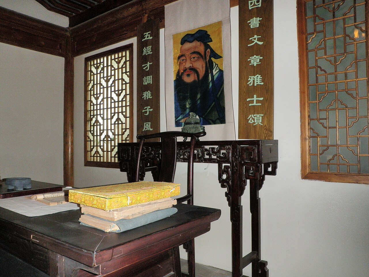 Traditional Confucian study room at Nanjing Number 1 Middle School with Confucius portrait, calligraphy scrolls, and classical texts on a carved wooden desk