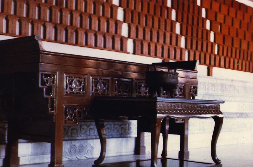 Chinese ancestral hall with carved altar table, incense burner, and rows of wooden spirit tablets