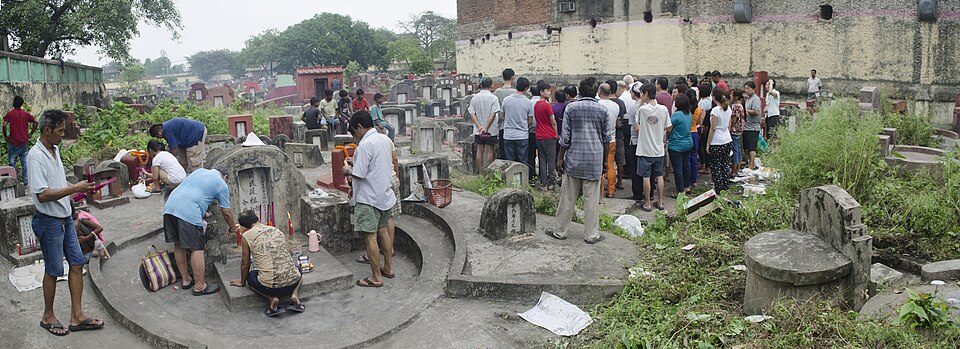 Chinese family sweeping an ancestral tomb and placing offerings during Qingming tomb-sweeping festival