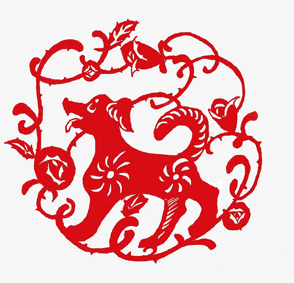 Red paper cutting of a Chinese zodiac dog surrounded by floral designs in traditional jianzhi style